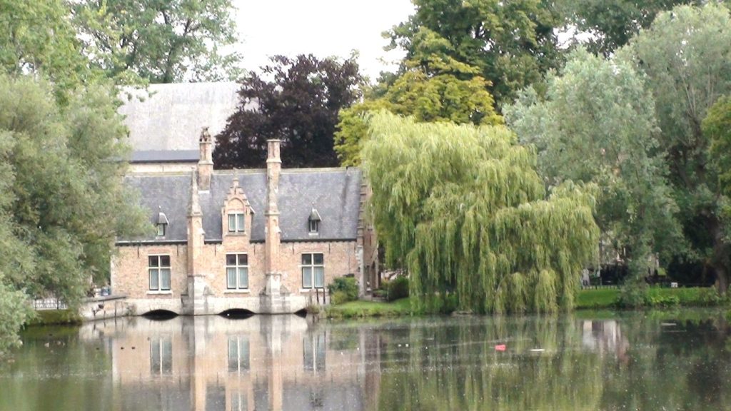 Edificio de estilo gótico flamenco reflejado en el agua de un canal tranquilo en Brujas