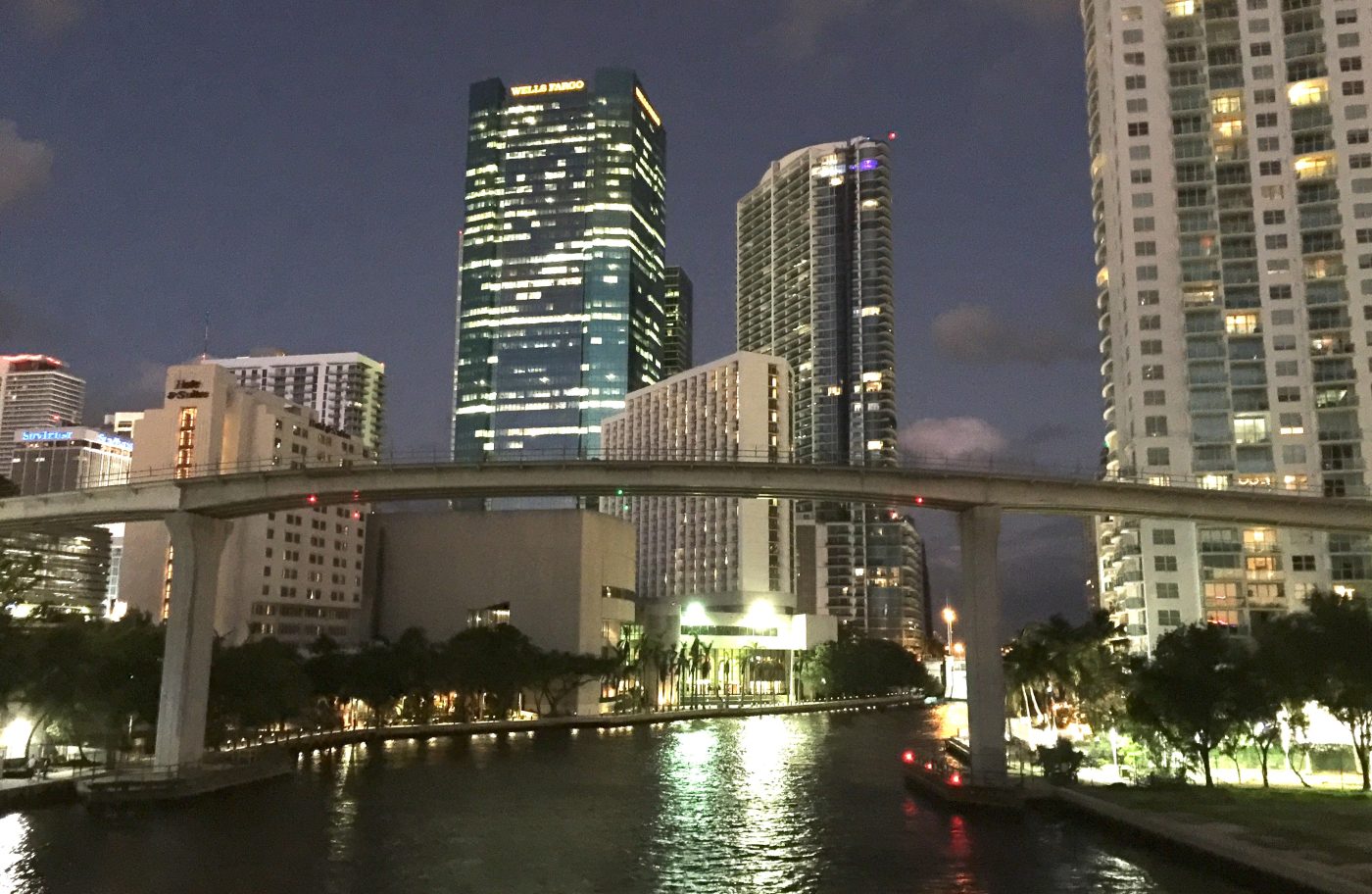Vista nocturna del río Miami canalizado con el edificio de Wells Fargo al fondo