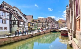 Vista del canal de Petite Venise en Colmar, con casas de colores reflejadas en el agua y turistas paseando