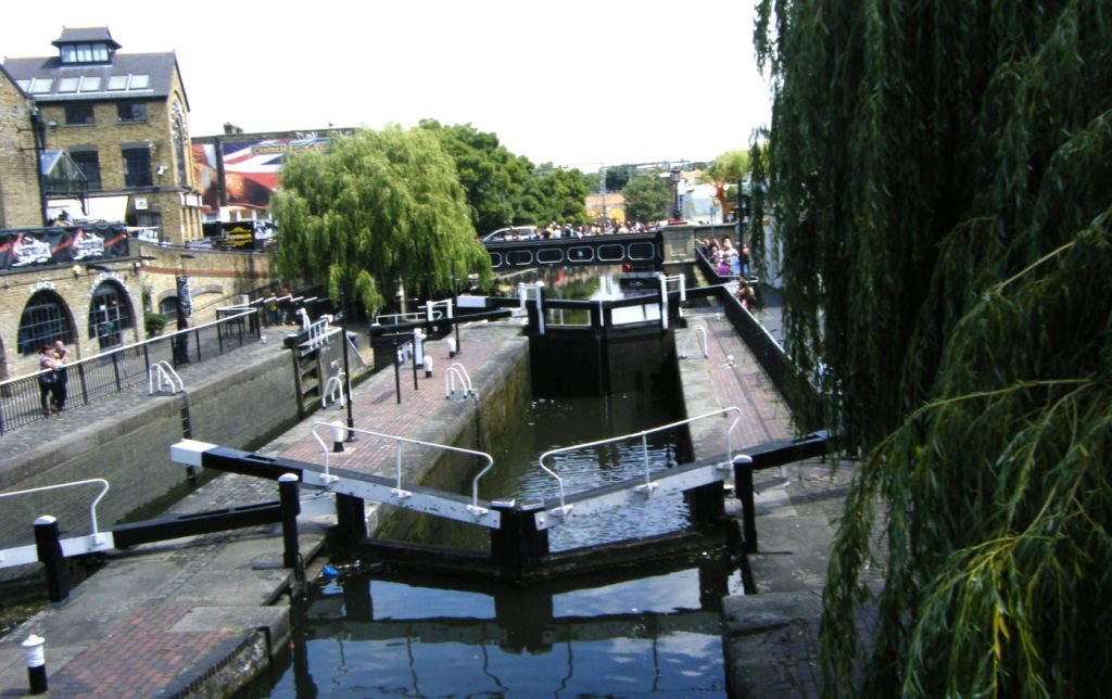 Vista de las esclusas del canal en Camden, Londres, con edificios industriales y árboles alrededor