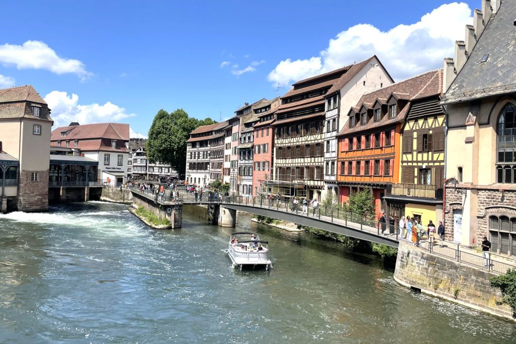 Barco turístico navegando por el canal de la Petite France en Estrasburgo, rodeado de casas tradicionales